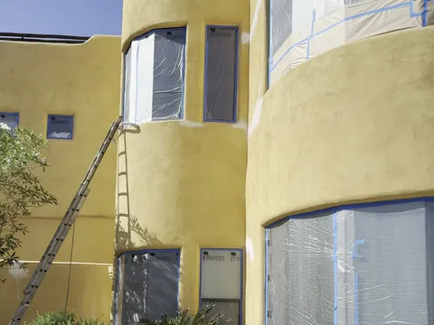 Before — Curved stucco elevations of Fountain Hills AZ custom home masked for spraying and after fresh gold exterior paint